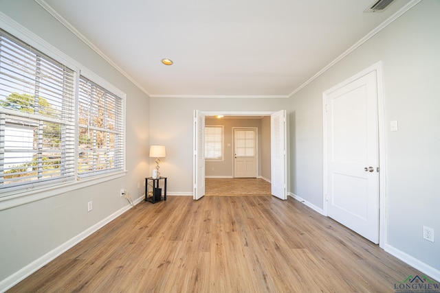 spare room with light hardwood / wood-style flooring, a wealth of natural light, and crown molding