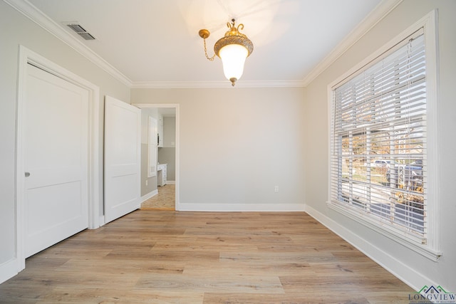 unfurnished room featuring ornamental molding, a wealth of natural light, and light hardwood / wood-style flooring