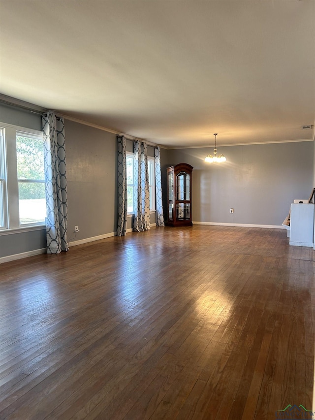 unfurnished living room with a notable chandelier, dark hardwood / wood-style floors, and ornamental molding