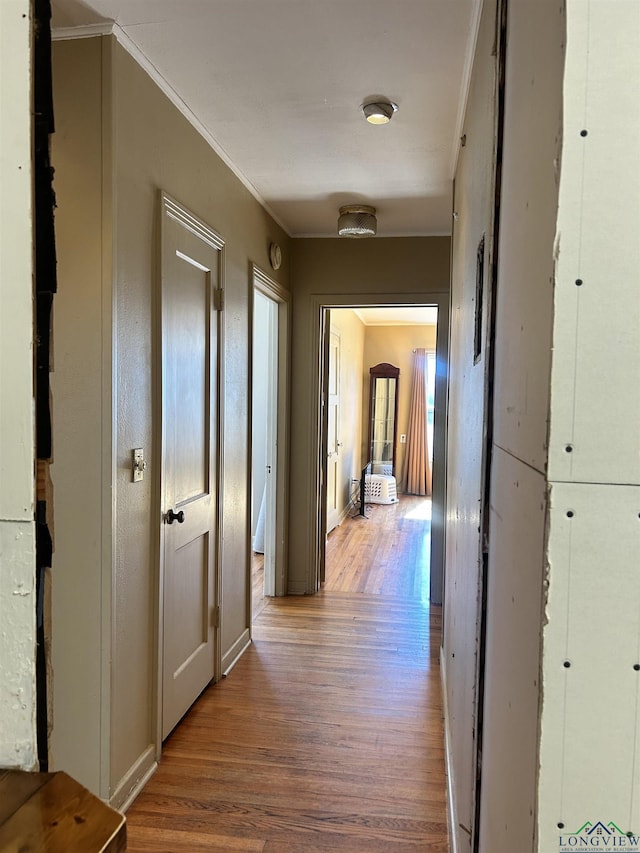 hallway with hardwood / wood-style flooring and ornamental molding