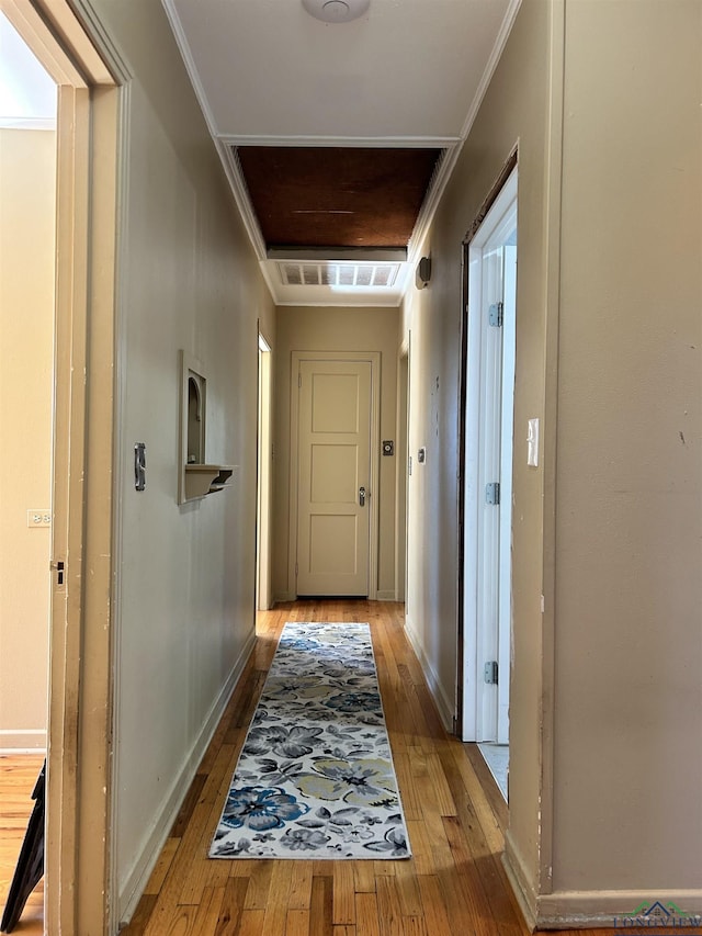 hallway with light hardwood / wood-style floors and crown molding