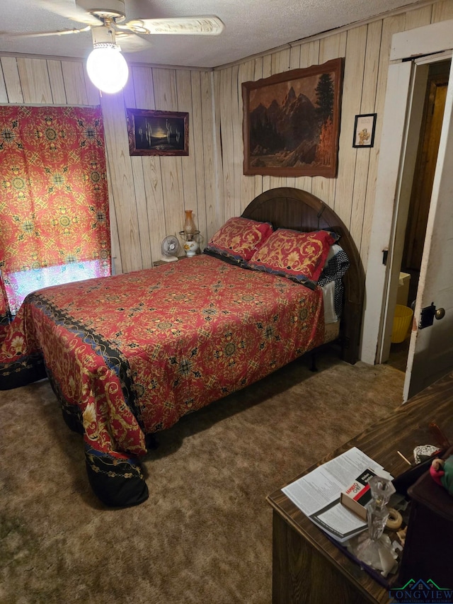 carpeted bedroom featuring ceiling fan, wooden walls, and a textured ceiling