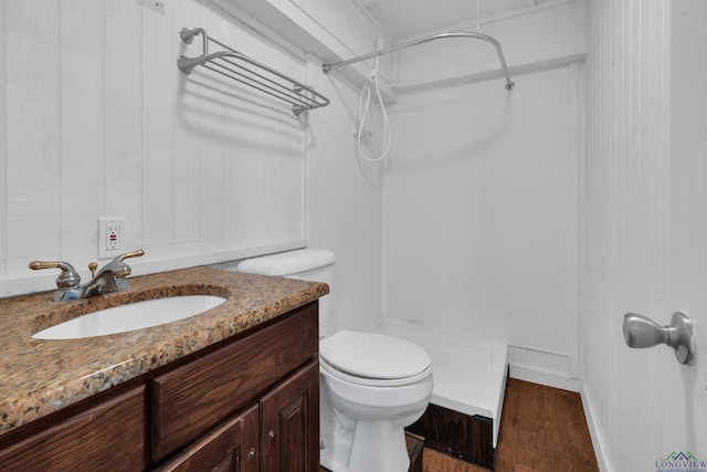 bathroom with a shower, vanity, hardwood / wood-style flooring, and toilet