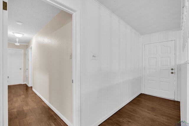 corridor with a textured ceiling and dark wood-type flooring