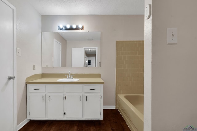 bathroom with hardwood / wood-style floors, vanity, washtub / shower combination, and a textured ceiling