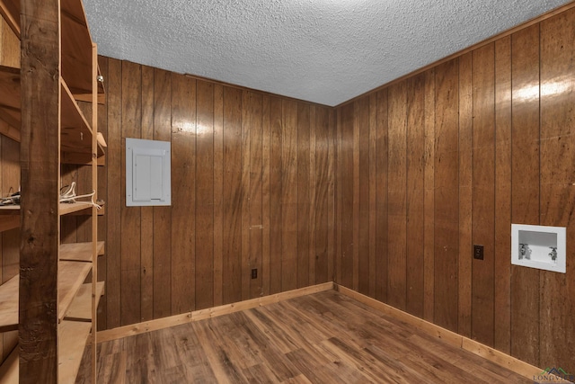 empty room featuring electric panel, wood walls, hardwood / wood-style floors, and a textured ceiling