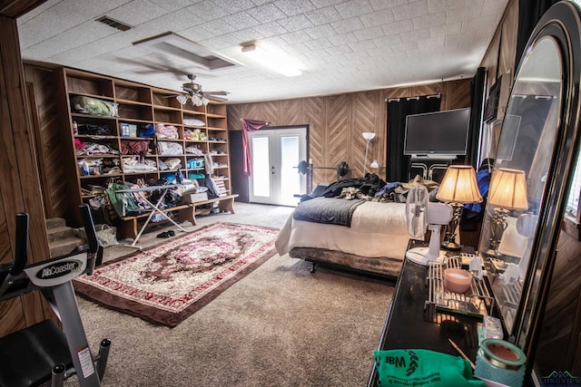 bedroom featuring wood walls, french doors, carpet floors, and ceiling fan