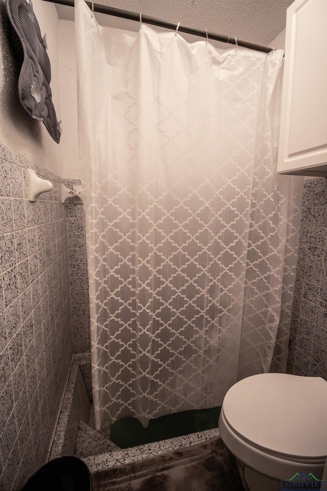 bathroom featuring walk in shower, a textured ceiling, and toilet