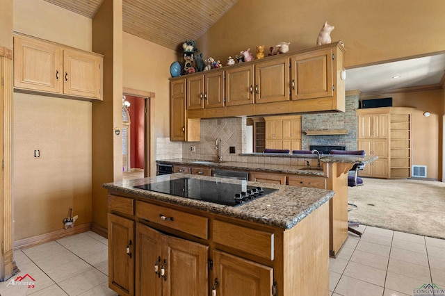 kitchen with light tile patterned floors, black electric cooktop, a kitchen island, visible vents, and backsplash