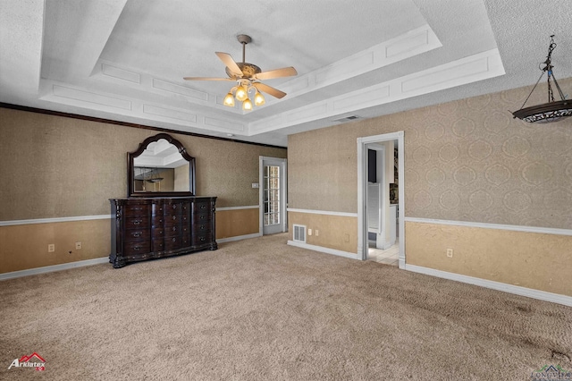 interior space with wallpapered walls, visible vents, a raised ceiling, carpet, and a textured ceiling