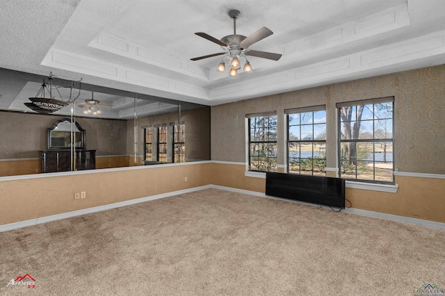 carpeted empty room with a ceiling fan, baseboards, a tray ceiling, and a textured ceiling