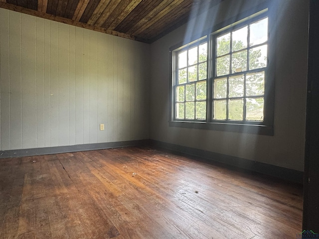 spare room featuring wooden ceiling, wood walls, and hardwood / wood-style floors