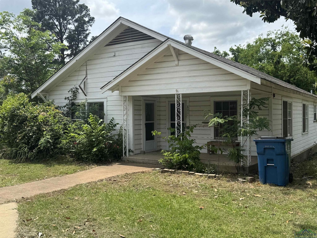 bungalow-style home with covered porch and a front lawn
