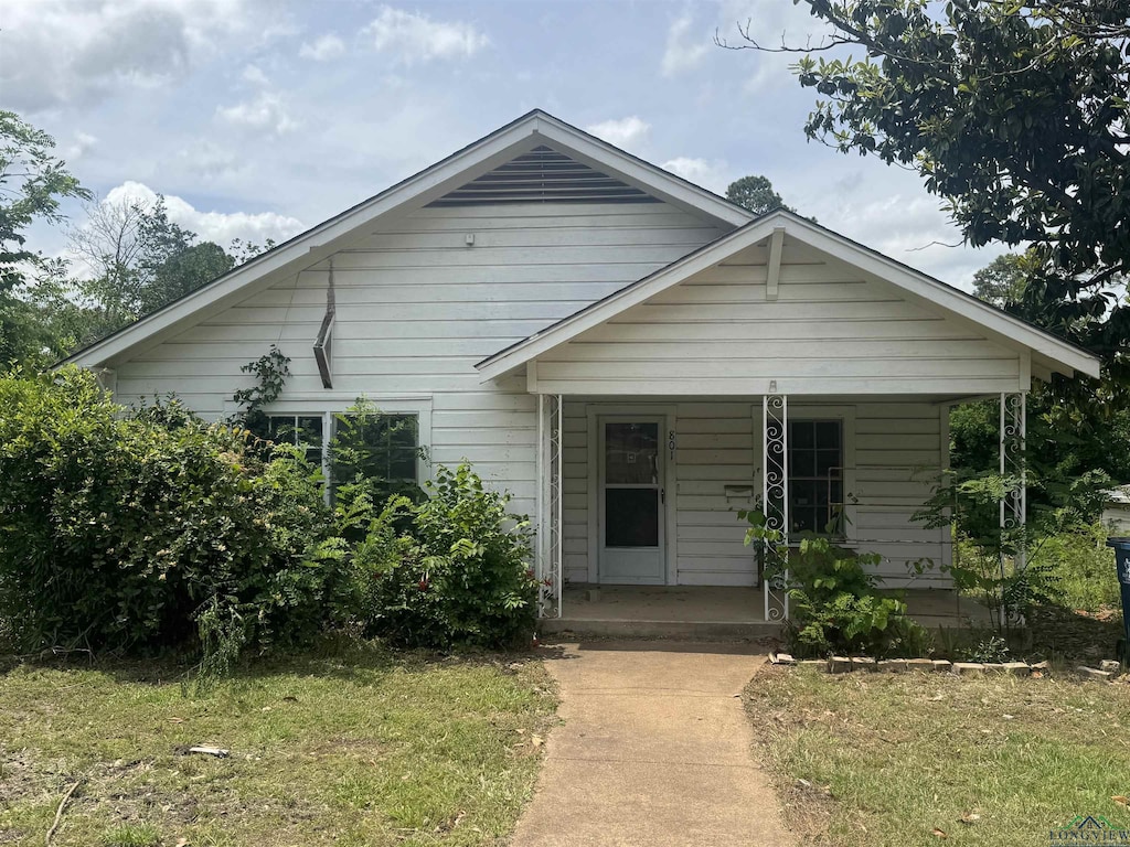 bungalow-style home with covered porch and a front yard