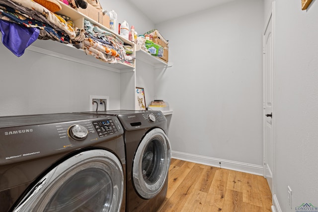 clothes washing area featuring light wood-type flooring, laundry area, baseboards, and washer and clothes dryer