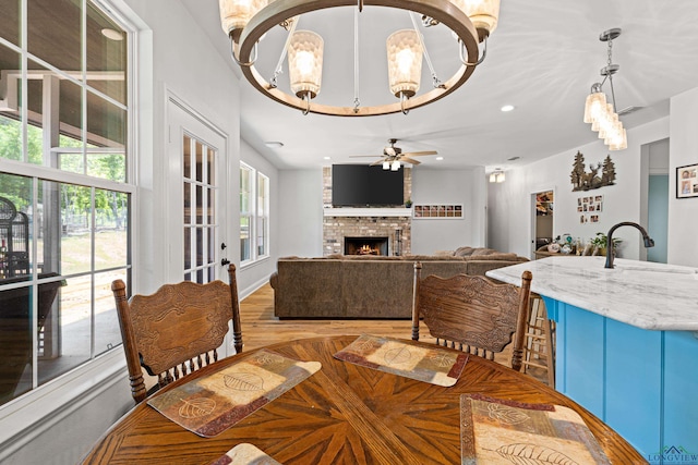 dining room with light wood-type flooring, a brick fireplace, ceiling fan, and recessed lighting