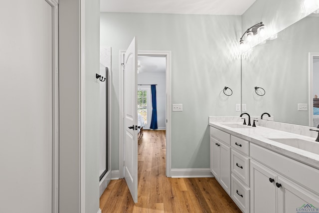 full bathroom with double vanity, ensuite bathroom, a sink, and wood finished floors