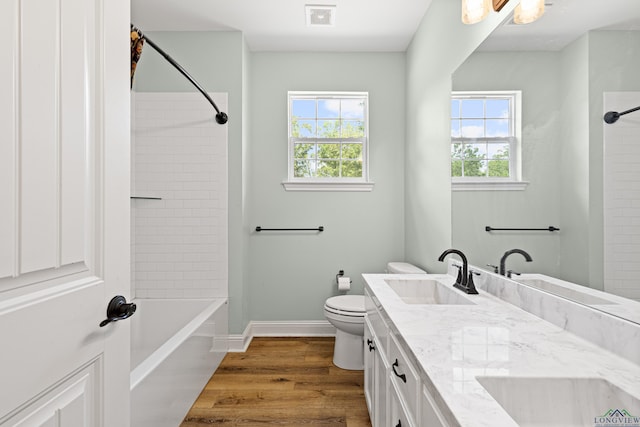 full bathroom featuring double vanity, a healthy amount of sunlight, a sink, and wood finished floors