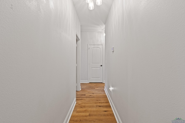 hallway with light wood-type flooring and baseboards