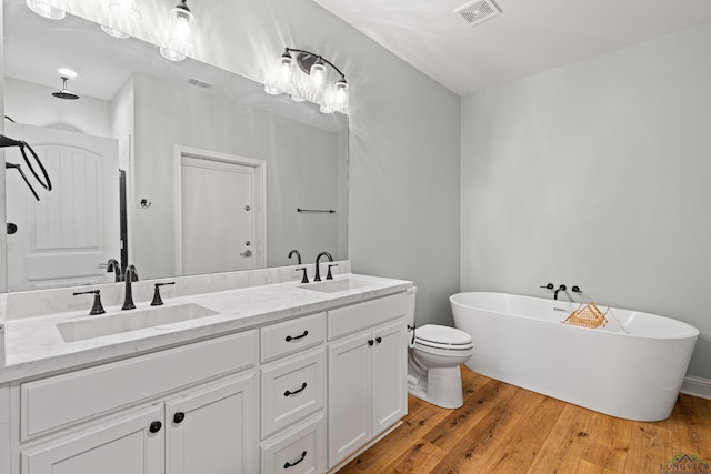 full bath featuring a soaking tub, visible vents, a sink, and hardwood / wood-style floors