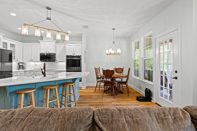 kitchen featuring decorative light fixtures, white cabinetry, open floor plan, appliances with stainless steel finishes, and glass insert cabinets