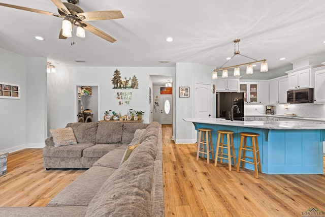 living area with light wood-style floors, visible vents, baseboards, and a ceiling fan