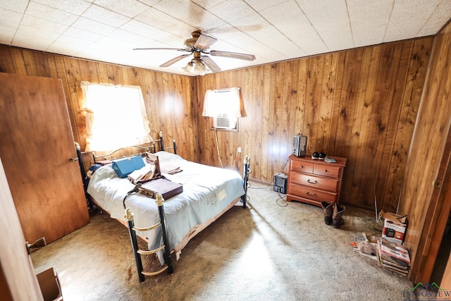 bedroom with ceiling fan and wood walls