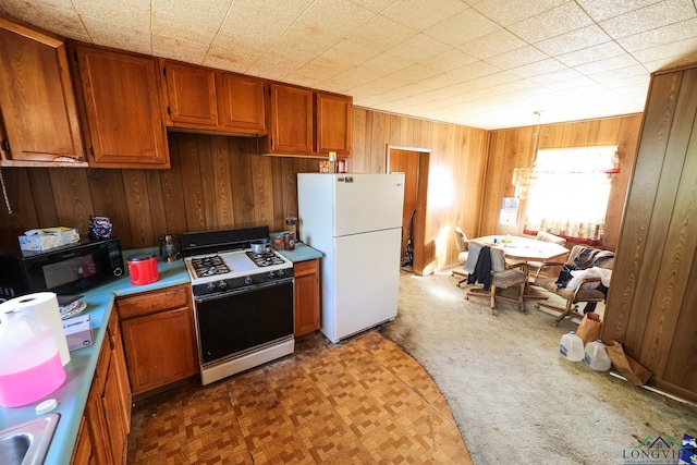 kitchen featuring wood walls, sink, and white appliances