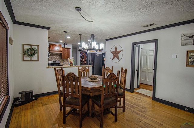 dining space featuring a notable chandelier, light hardwood / wood-style floors, and crown molding