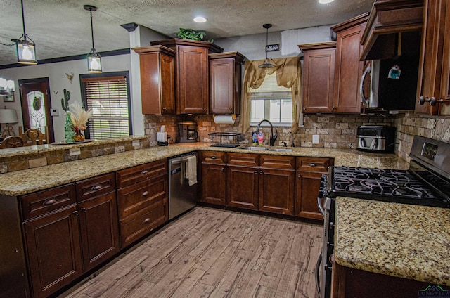 kitchen with pendant lighting, sink, a textured ceiling, appliances with stainless steel finishes, and light hardwood / wood-style floors