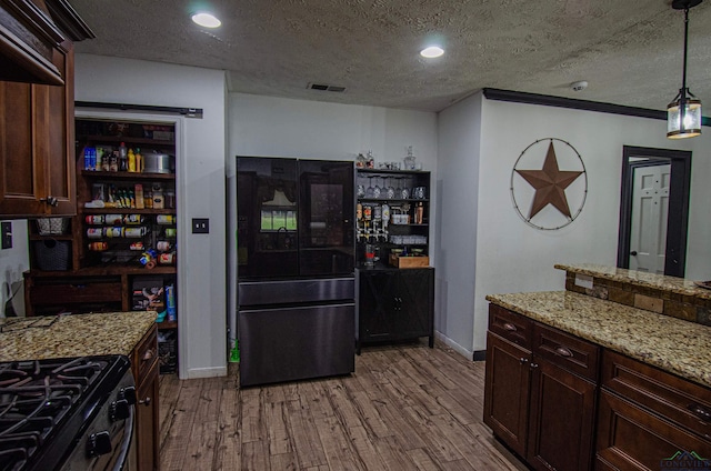 kitchen featuring light stone countertops, pendant lighting, a textured ceiling, light hardwood / wood-style floors, and dark brown cabinets