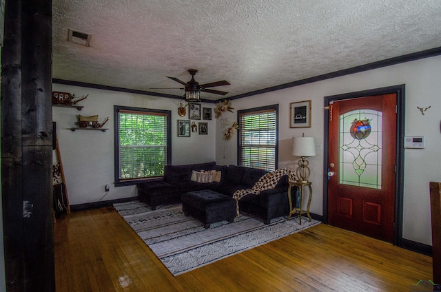 living room with hardwood / wood-style flooring, ceiling fan, ornamental molding, and a textured ceiling