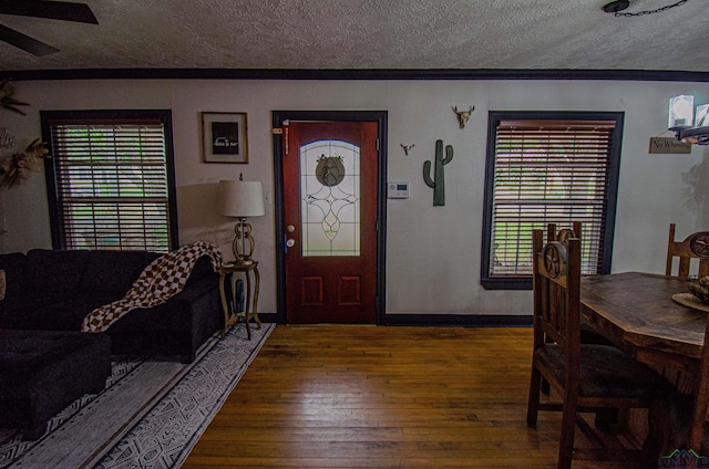 foyer entrance featuring ceiling fan, plenty of natural light, wood-type flooring, and a textured ceiling