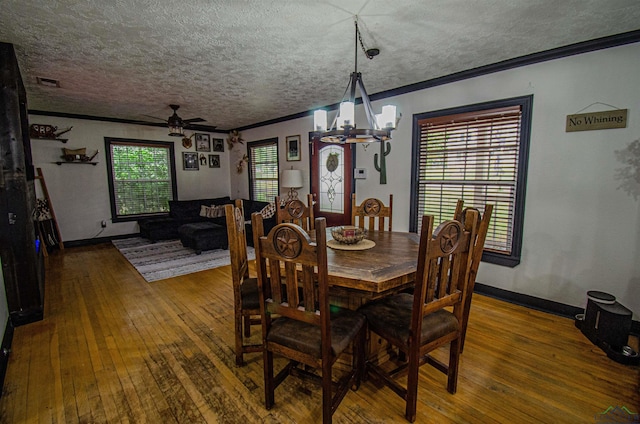 dining space featuring ceiling fan with notable chandelier, wood-type flooring, and ornamental molding