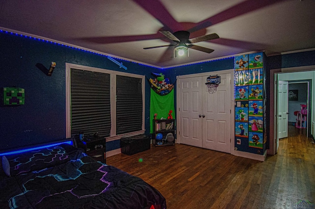 bedroom with ceiling fan, wood-type flooring, ornamental molding, and a closet