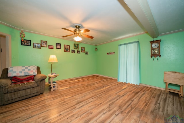 living area featuring hardwood / wood-style flooring, ceiling fan, ornamental molding, and beamed ceiling