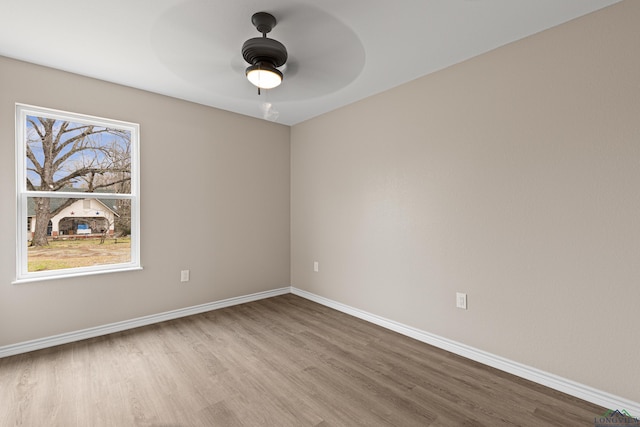 empty room featuring ceiling fan, baseboards, and wood finished floors