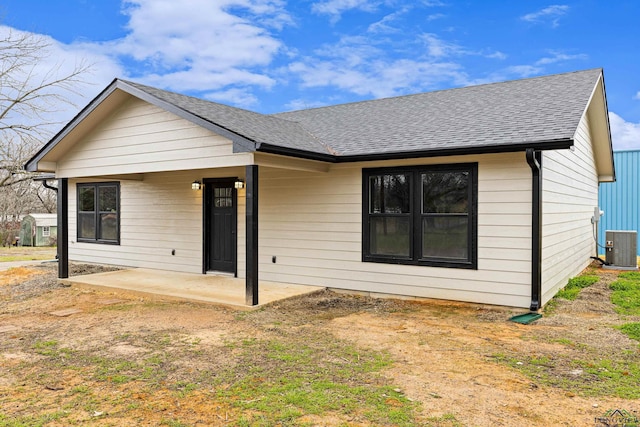 rear view of property with a patio area, central air condition unit, and roof with shingles