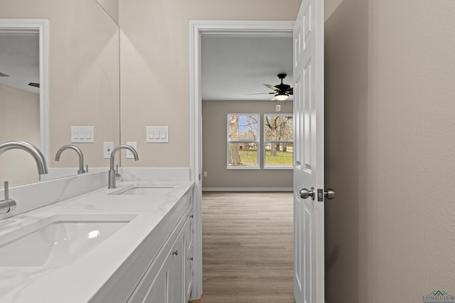 full bath with double vanity, wood finished floors, ceiling fan, and a sink