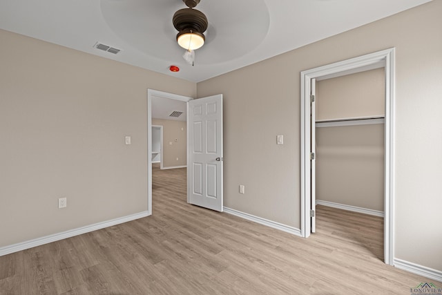 unfurnished bedroom featuring light wood-style flooring, baseboards, visible vents, and a closet