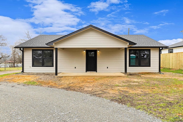 view of front of property with roof with shingles and fence