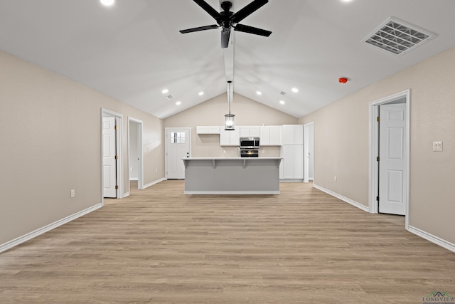 kitchen featuring stainless steel microwave, visible vents, open floor plan, light wood-style floors, and white cabinetry