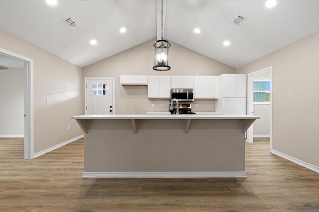 kitchen with visible vents, stainless steel microwave, a spacious island, white cabinetry, and light wood-style floors