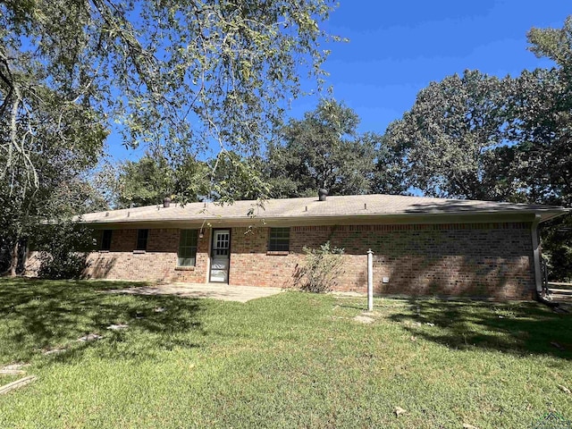 rear view of house featuring brick siding, a lawn, and a patio