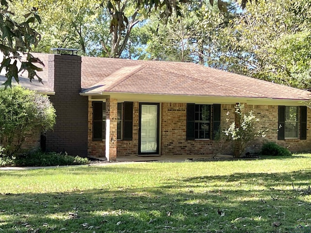 ranch-style home featuring a shingled roof, a front yard, and brick siding