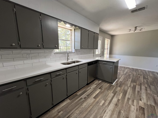 kitchen with dishwasher, dark wood-type flooring, sink, tasteful backsplash, and kitchen peninsula