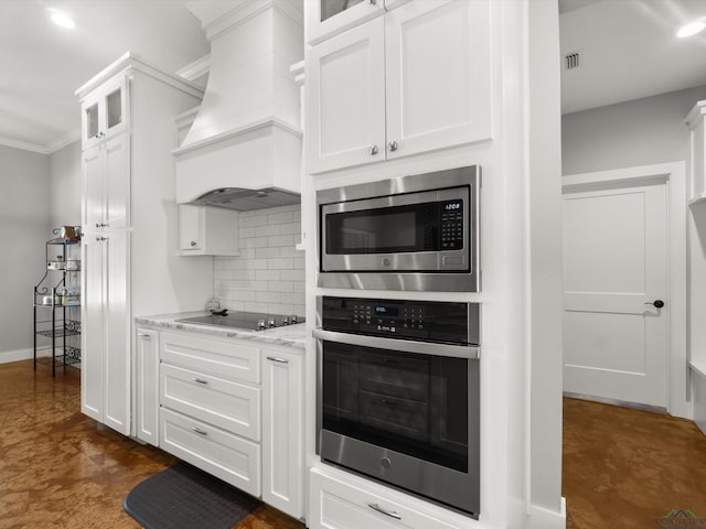 kitchen featuring white cabinets, stainless steel appliances, premium range hood, ornamental molding, and light stone counters