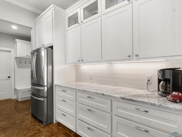 kitchen featuring crown molding, decorative backsplash, stainless steel refrigerator with ice dispenser, white cabinets, and light stone counters