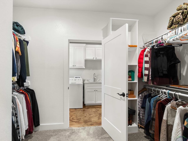 spacious closet featuring sink, washer / dryer, and light colored carpet