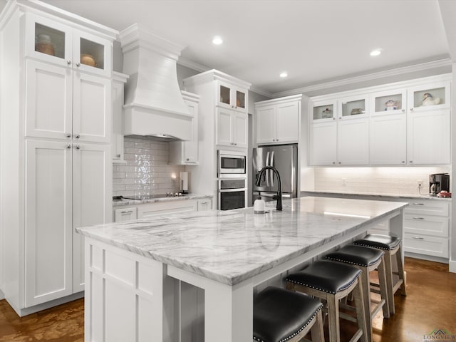 kitchen with a large island with sink, white cabinetry, and appliances with stainless steel finishes